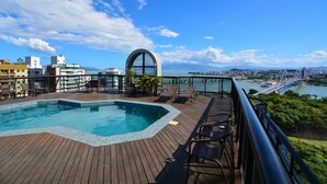 A rooftop pool area with a view of a cityscape and a bridge. - Flat no Central Park Residence (Florianopolis)