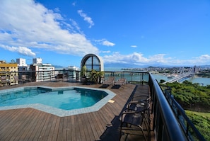 Un área de piscina en la azotea con vista a un paisaje urbano y un puente.