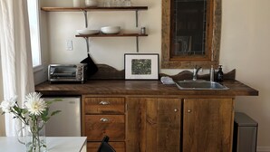 A compact kitchen with wooden cabinets, a built-in oven, a sink, and a window above the counter.