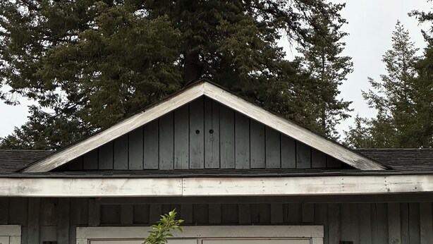 A rustic wooden house with a large front door and two lit windows.