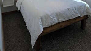 A neatly made bed with white linens, two bedside tables with lamps, and a hanging light fixture.