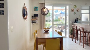 Une cuisine moderne avec un coin repas, comprenant une grande table, des chaises et une vue sur l’extérieur.