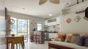 Un salon moderne comprenant un canapé, une table basse et un coin repas avec des chaises.