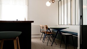 A modern kitchen with wooden flooring, a dining table with chairs, and a pendant light.