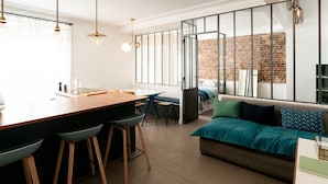A modern kitchen with a wooden island, bar stools, and pendant lighting.