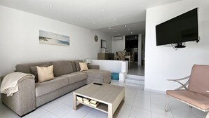 A modern living room with a grey sofa, a coffee table, and a TV mounted on the wall. - Albufeira Blue Wave Retreat 65 (Albufeira)