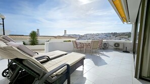 A rooftop terrace with lounge chairs, a table, and chairs. - Albufeira Blue Wave Retreat 65 by Rentals in Algarve (Albufeira)