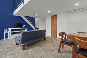 Un salon moderne avec un canapé, une table à manger en bois et un escalier.
