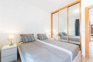 A bedroom with a bed, nightstands, a mirror, and a wardrobe.