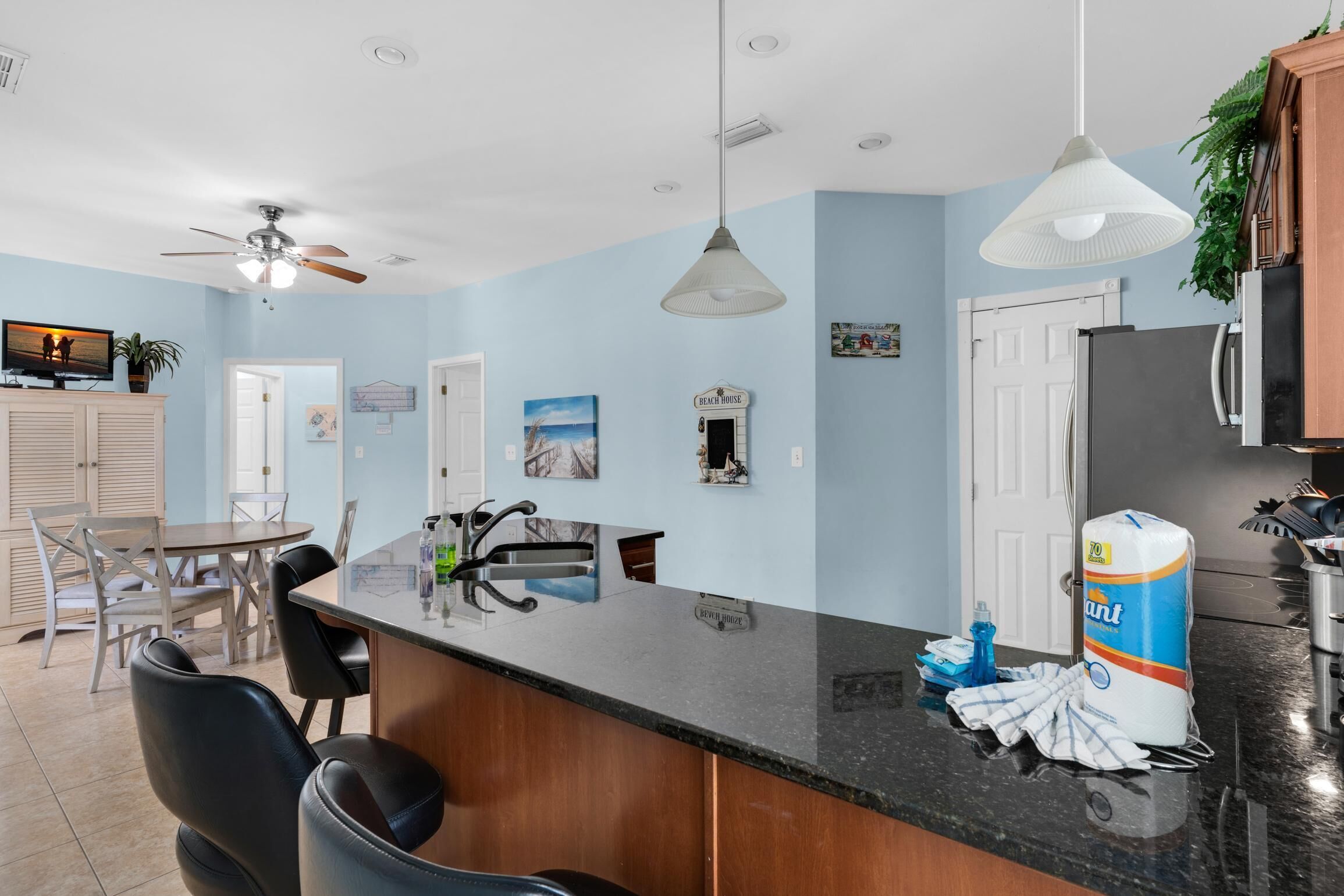 A modern kitchen with a black countertop, wooden cabinets, and a ceiling fan.