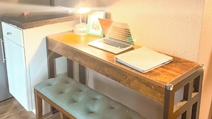 Un bureau en bois avec un ordinateur portable, une lampe et un carnet.