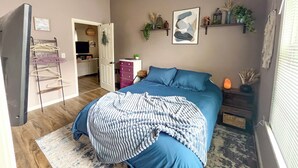 Une chambre à coucher comprenant un lit, une commode, un miroir et une porte donnant sur une autre pièce.