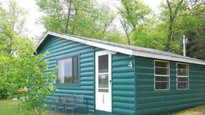 Une petite cabane en rondins, d’un seul étage, avec une porte et des fenêtres, portant le numéro 4, et entourée de verdure.