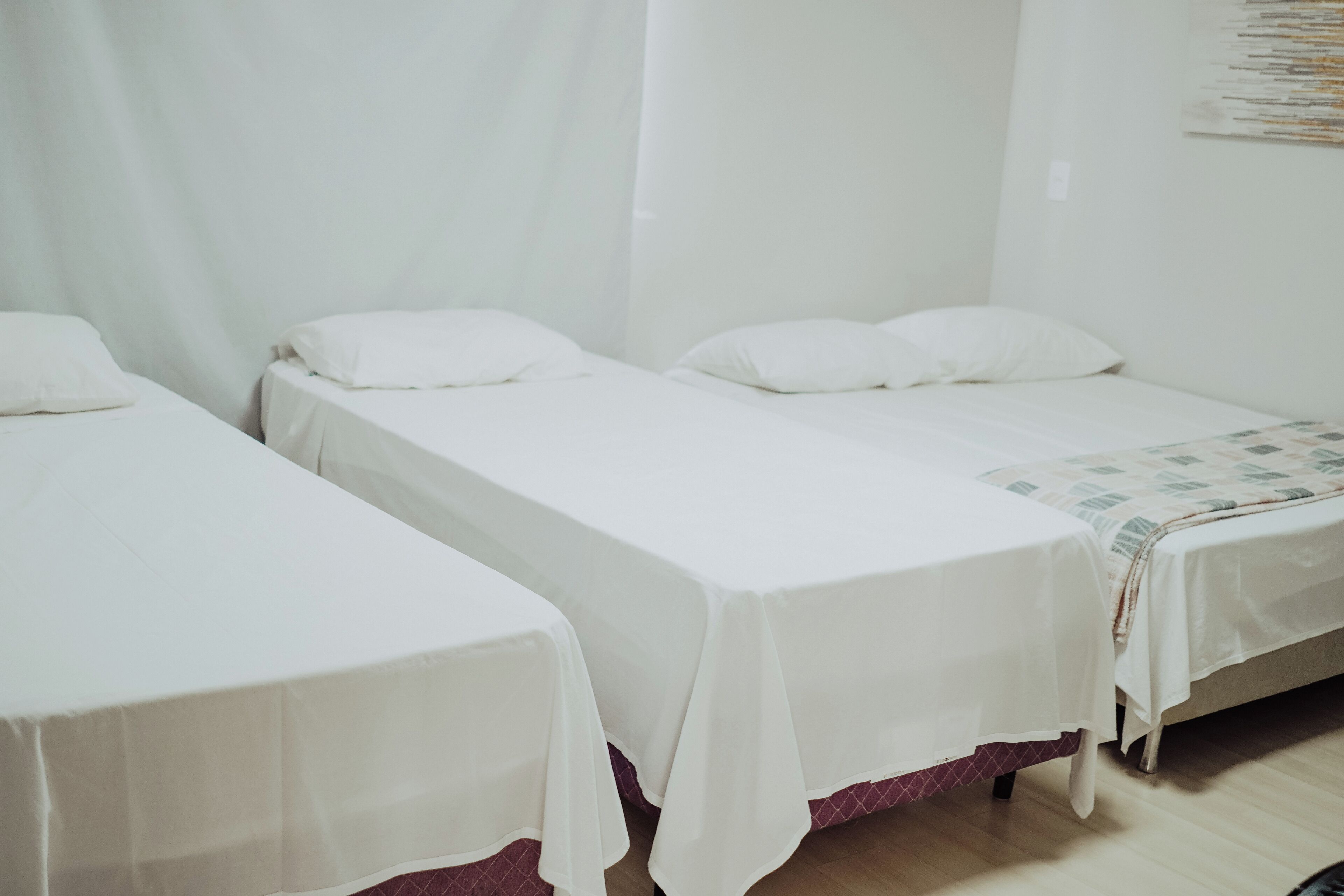 A room with two single beds, each with a white bedspread and pillows.