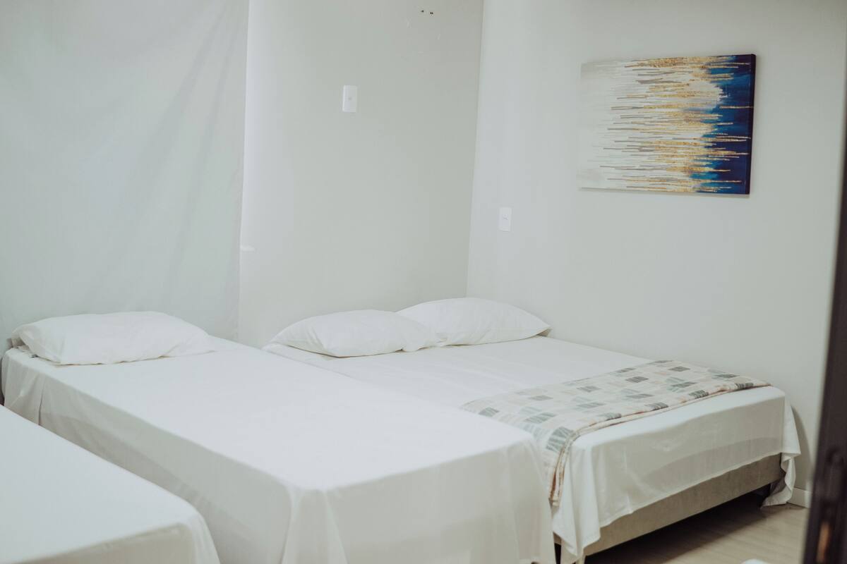 A room with two single beds, a small table, and a wall-mounted artwork.