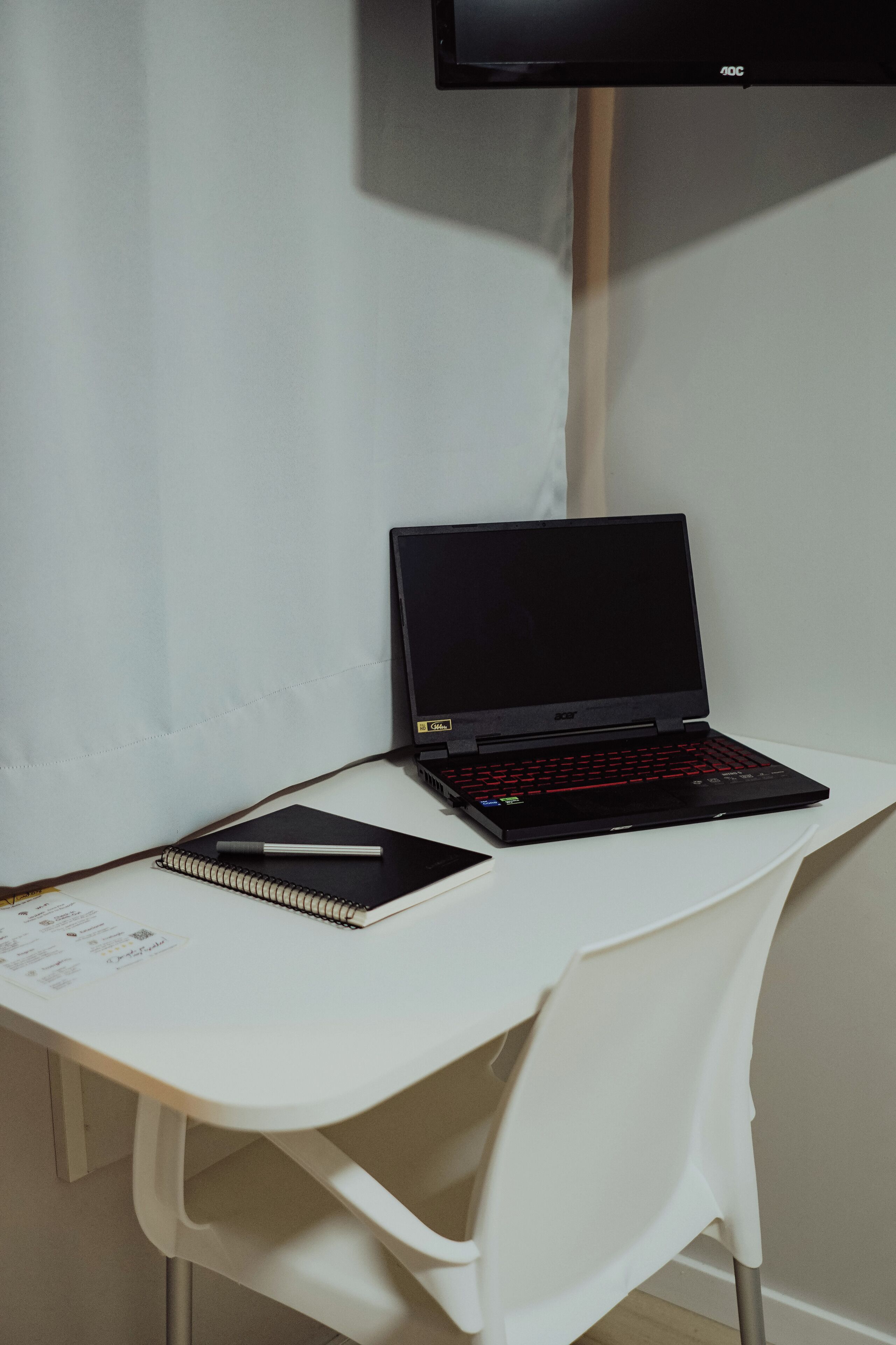 Un ordinateur portable sur un bureau blanc, avec un carnet et un stylo à côté.