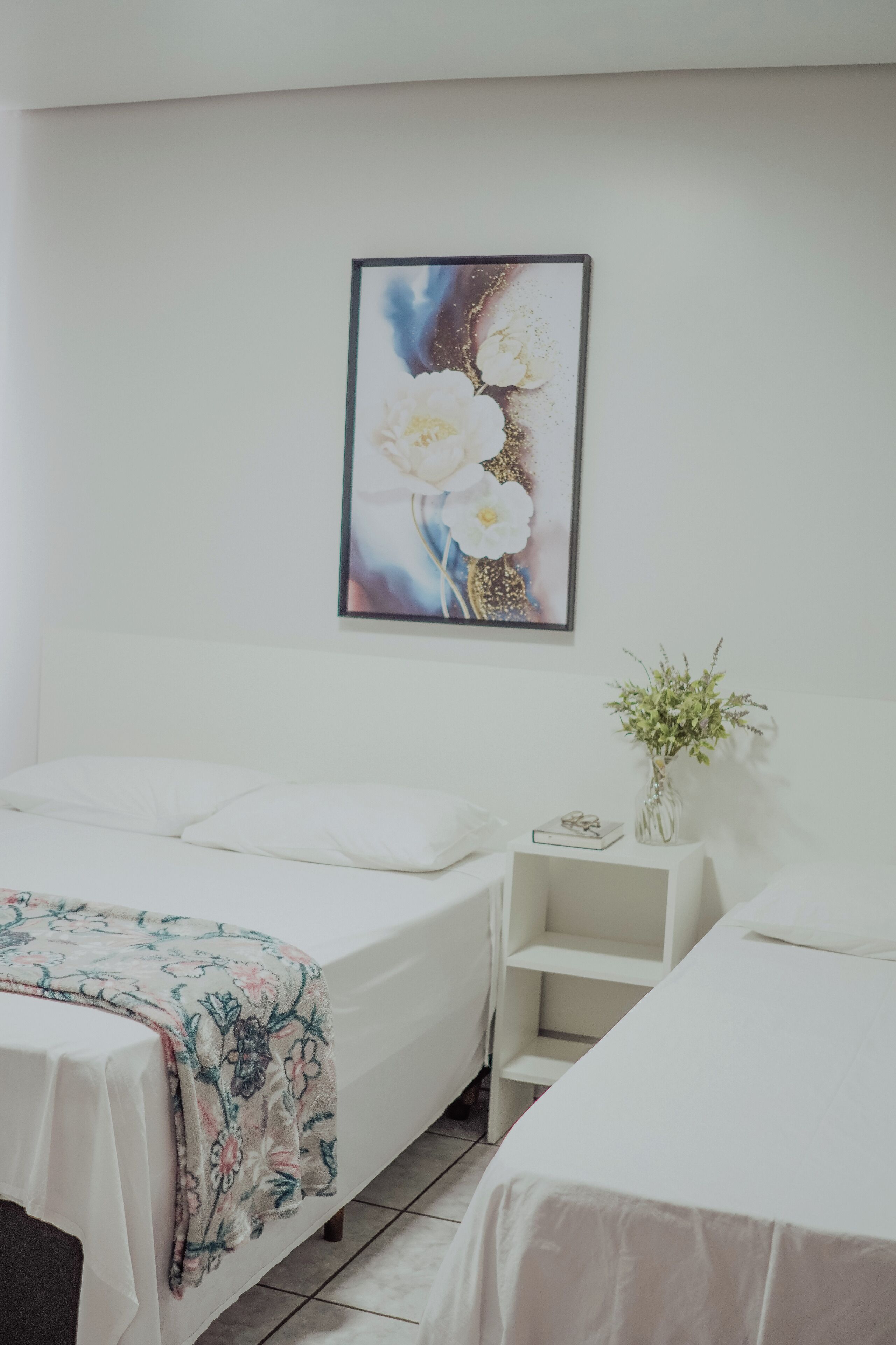 A hotel room with a bed, a nightstand, and a wall-mounted picture.