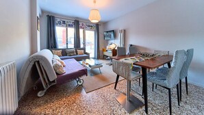 A modern living room with a sofa, dining table, chairs, and a TV. - 𓃹 Bohemian Escape: Terrace, Parking by Ski Resort (Ordino)