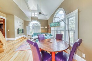 A spacious room with a wooden dining table and purple chairs, large windows, and a staircase leading to another level. - The Farmhouse at South Hero (South Hero)