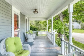 A porch with wicker chairs and a wooden deck. - The Farmhouse at South Hero (South Hero)