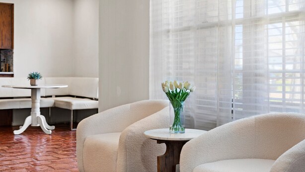 A modern room with a white sofa, a round table, and a vase of white flowers. - Spacious yet cozy 4-bedroom house in a PRIME Location in Dallas! (Dallas)