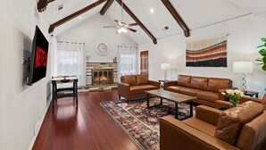 A spacious living room with a fireplace, leather sofas, a coffee table, and a television mounted on the wall. - Spacious yet cozy 4-bedroom house in a PRIME Location in Dallas! (Dallas)