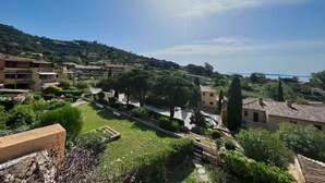 A residential area with houses, a road, and a hill in the background. - St Clair - Sea view apartment (Le Lavandou)