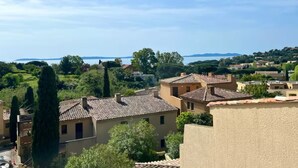 A residential area with terracotta-roofed buildings, lush greenery, and a distant view of the sea. - St Clair - Sea view apartment (Le Lavandou)