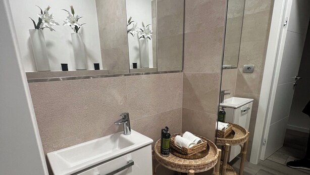A modern bathroom with a white sink, mirror, and wicker baskets. - LuxArt City SPA Residence Krk (Krk)