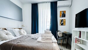 Ein Hotelzimmer mit Bett, Schreibtisch, Stuhl, Fernseher und Bücherregal.