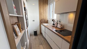 Eine moderne Küche mit Holzboden, weißen Schränken und einem eingebauten Backofen.