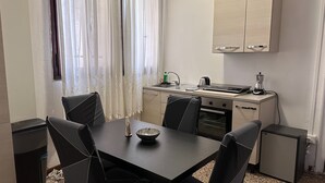 Una cocina compacta con mesa, sillas, un refrigerador pequeño y un horno empotrado.