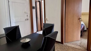 Una habitación con una mesa de comedor, sillas, un tazón y una cama al fondo.