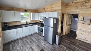 Une cuisine moderne avec des meubles blancs, un réfrigérateur en acier inoxydable et un plancher en bois.