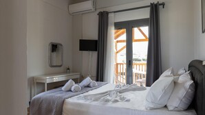 Ein Hotelzimmer mit Bett, Schreibtisch, Flachbildfernseher und einem Balkon mit Holzgeländer.