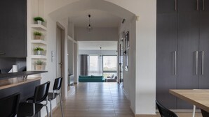 Eine moderne Küche mit Kochinsel, schwarzen Barhocker und einem blaugrünen Sofa im Essbereich.
