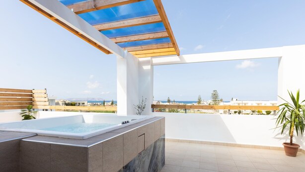 Eine Dachterrasse mit Whirlpool, einer Pergola und Blick aufs Meer.