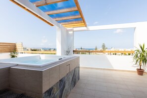 A rooftop terrace with a hot tub, a pergola, and a view of the sea.
