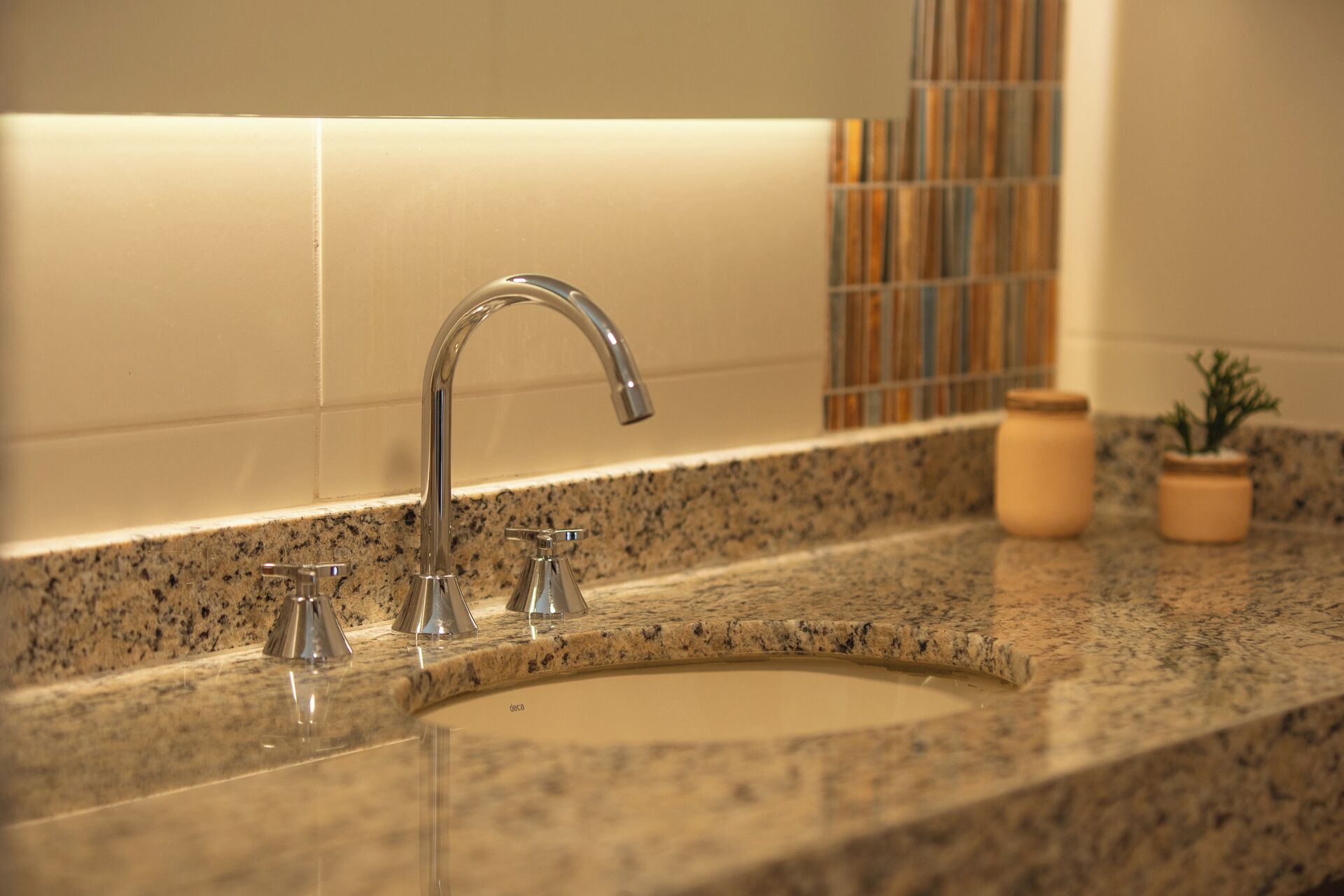 A bathroom sink with a single faucet, a granite countertop, and a tiled backsplash.