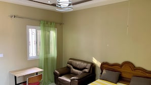 Un dormitorio con cama, escritorio y sillón de cuero.