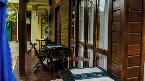 An outdoor seating area with wooden tables and chairs, a wooden door, and a view of the street.