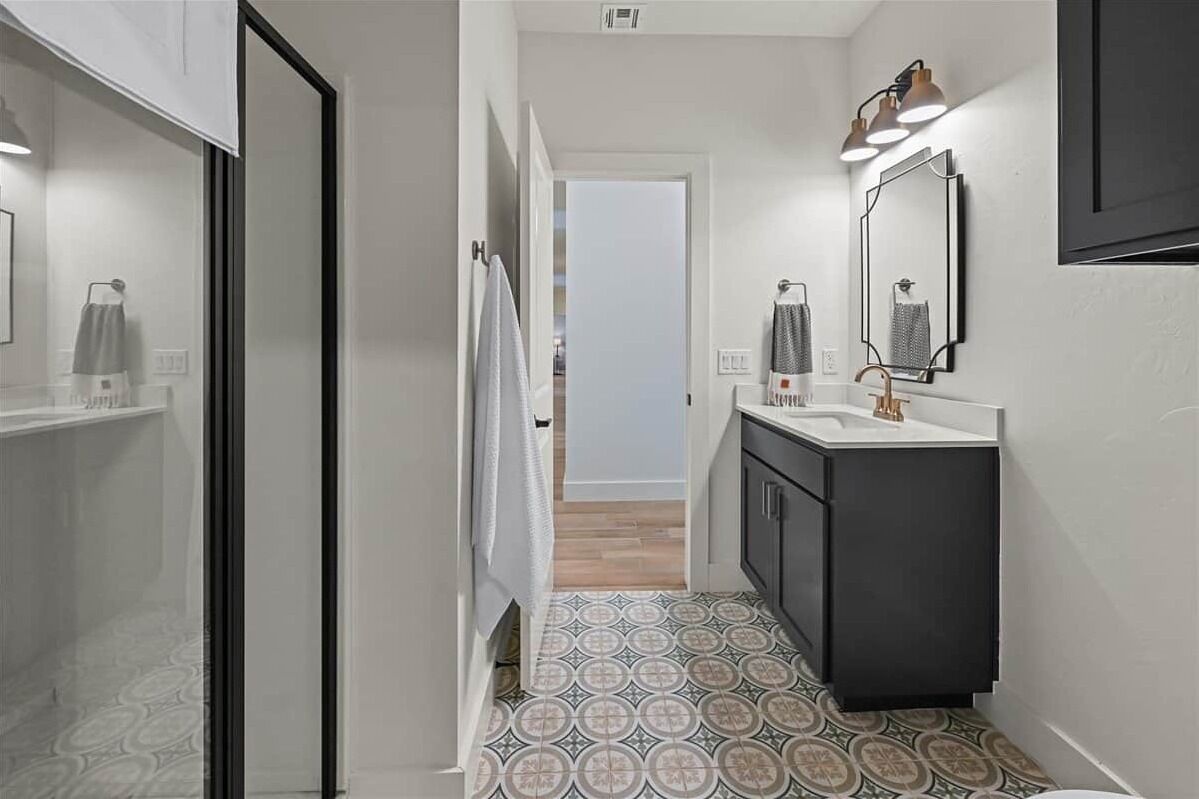 A narrow hallway leading to a bathroom with a sink, mirror, and towel rack.