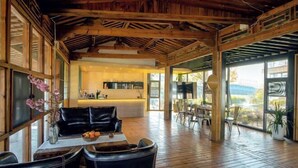 A spacious room with a wooden ceiling, a black leather sofa, a dining area with chairs, and large windows offering a view. - Heyuan Hotel (Dali City)