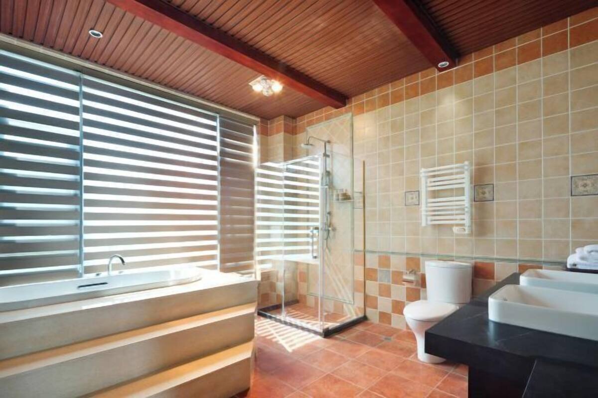 A bathroom with a large window, a shower, a toilet, and a sink.