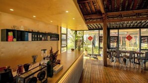 A wooden interior with a reception desk, shelves with tea and coffee, and a view of the outdoors. - Heyuan Hotel (Dali City)