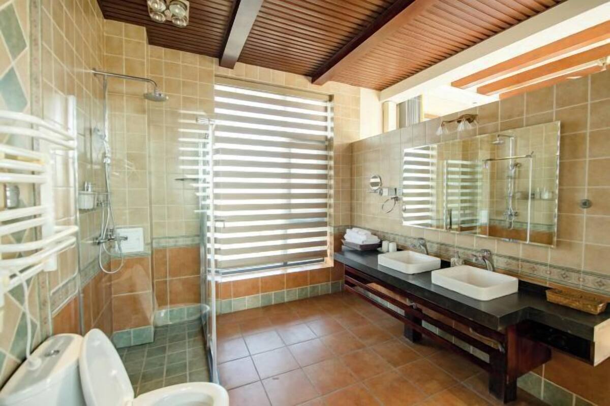 A modern bathroom with a shower, two sinks, and a large mirror.