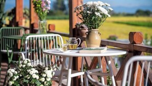 A patio with outdoor seating, a table with a book and a glass of tea, and a vase with flowers. - Heyuan Hotel (Dali City)