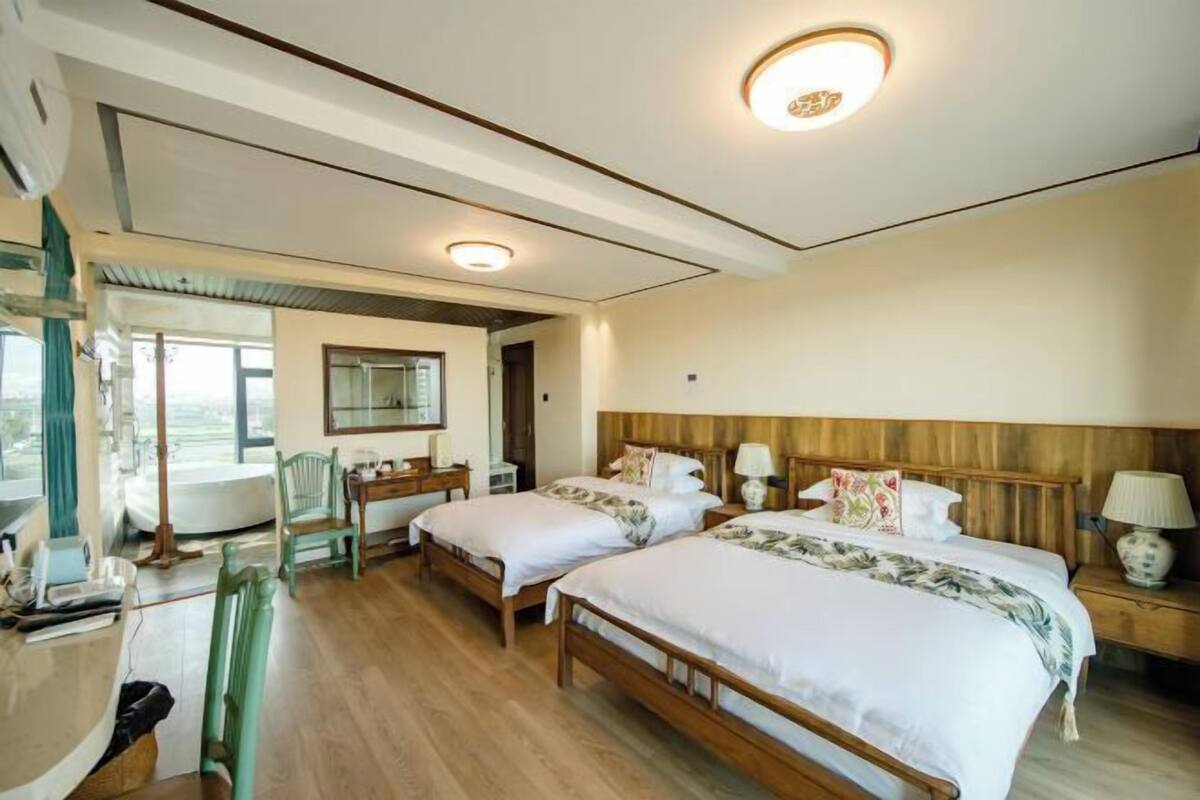 A hotel room with two beds, a desk, and a chair.
