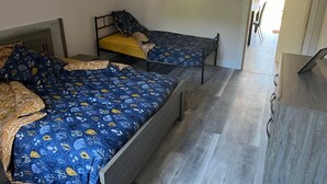 Ein Zimmer mit zwei Einzelbetten, Holzboden und einem kleinen Tisch.