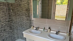 Ein Badezimmer mit zwei Waschbecken, einer Dusche und einem Spiegel.
